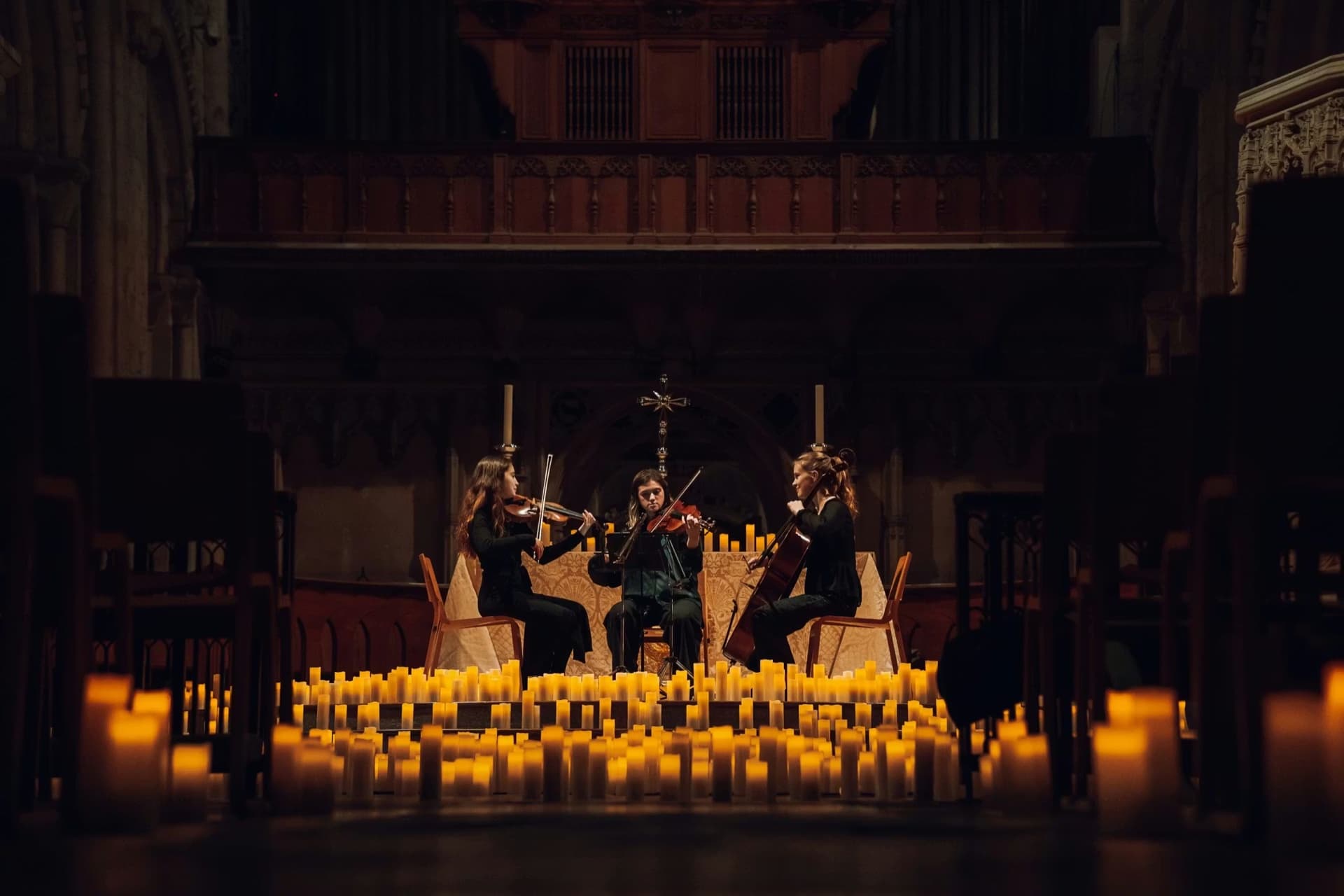 A string trio performing candlelit in a historic church